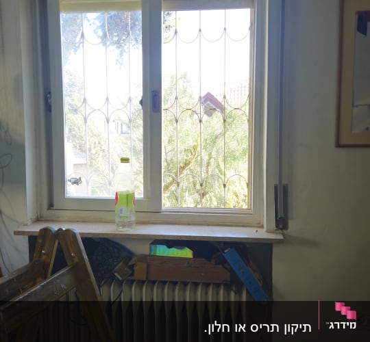 חלון עם תריסים וסולם בחדר פנימי
